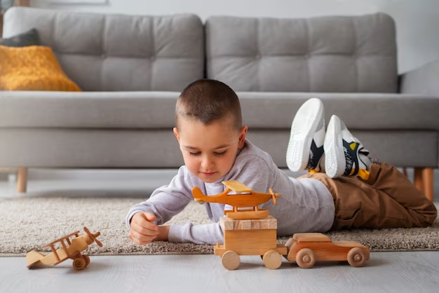 A boy child playing with a wooden toy car